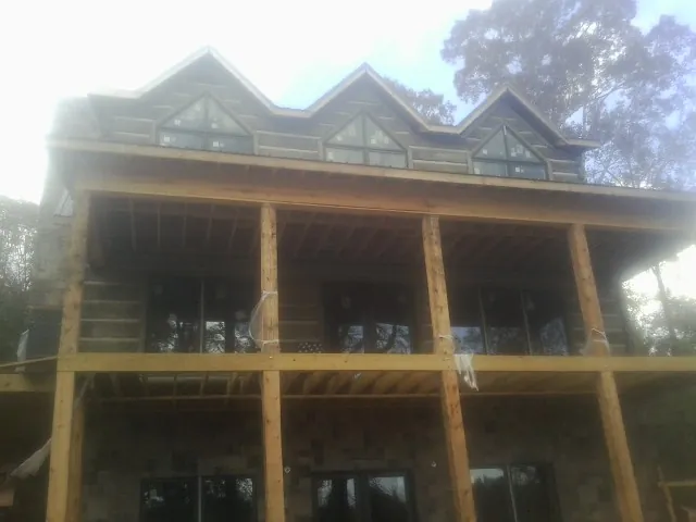 Dormers and porch framing on a large log home under construction — Roof Coating work by our crew in Nicholson