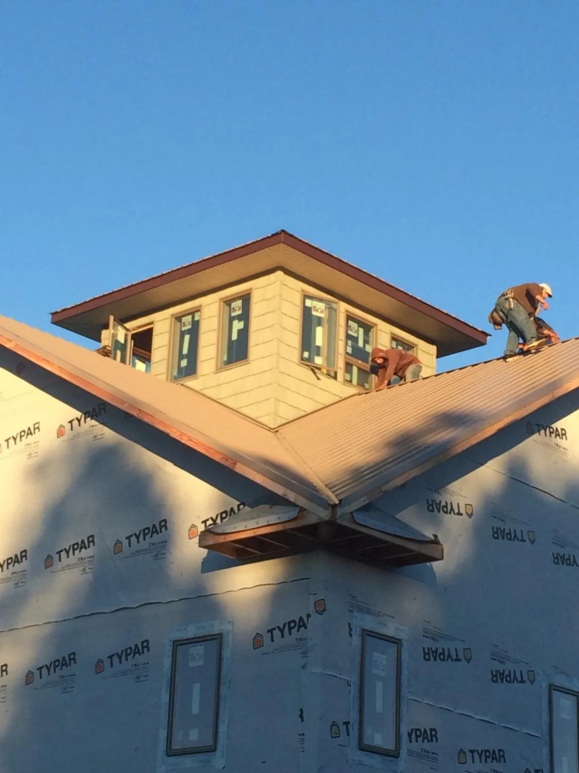Roofers working around a rooftop cupola on a new metal roof at sunset — Roof Waterproofing in Nicholson by Roofing Brothers